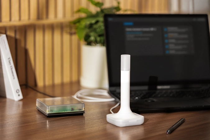 The Home Assistant Connect ZBT-2 device on a wooden desk, placed next to a laptop and a Home Assistant Green.